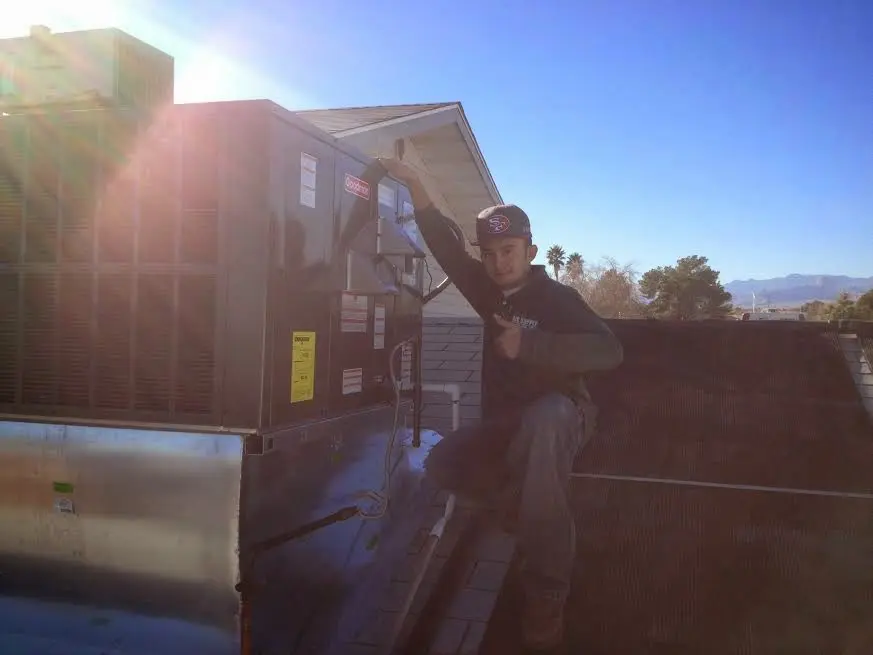HVAC technician performing AC Tune-Up on a rooftop unit in North Syracuse